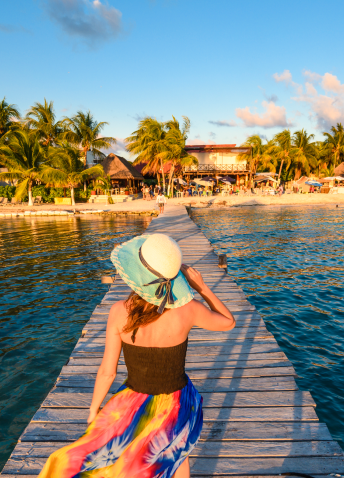 woman strolls along a wooden dock, enjoying the view of the water and surrounding scenery.  