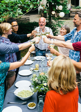 A group of people joyfully toasting with glasses at a dinner table, celebrating together during a meal.