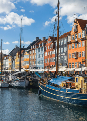 A river filled with boats in front of bright colored buildings in Copenhagen.