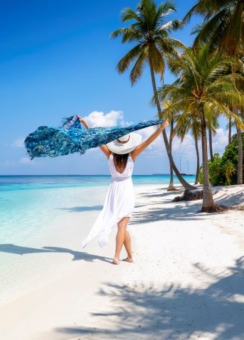 A woman walking on the beach enjoying the breeze on a clear day.