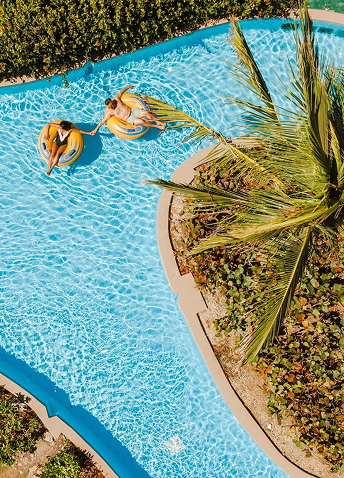 Two people floating on inflatable tubes down a lazy river at a Hard Rock Resort.