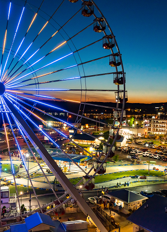 A lit up ferris wheel in Branson, MO as the sun sets behind the city.