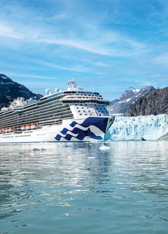 Large Princess Cruises ship sailing near a massive glacier and icebergs in Alaska.