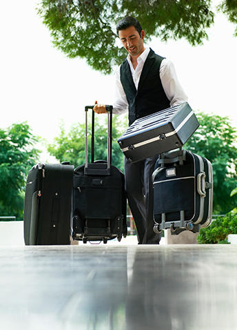 A man walking into a hotel with multiple pieces of luggage