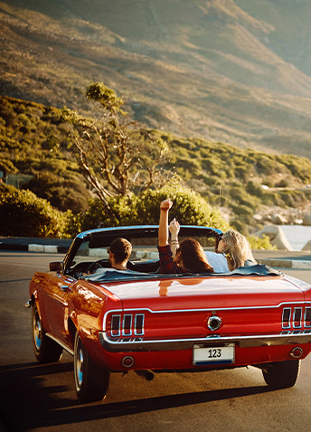 Friends riding in a vintage Ford Mustang down the highway
