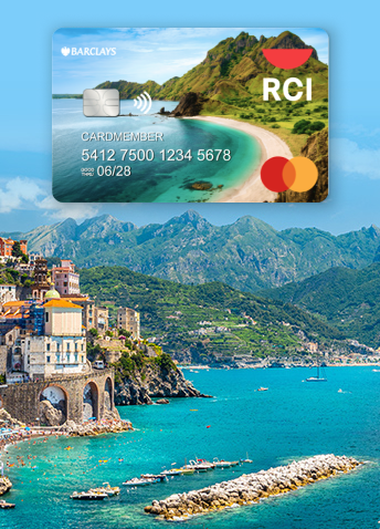 An aerial view of seaside village with the RCI Mastercard image floating above the lush green mountains in the distance