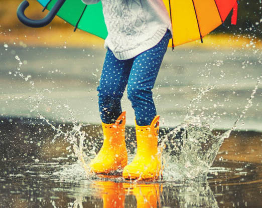 A child in galoshes splashing in a puddle