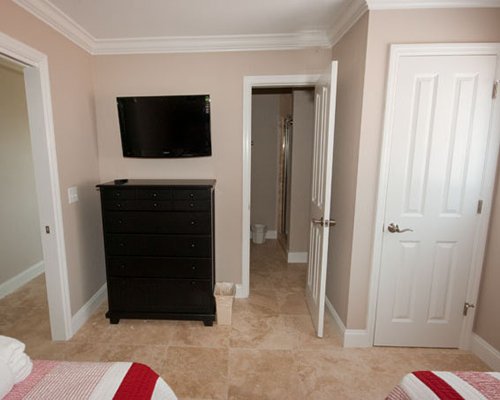 Bedroom with two beds, storage, bathroom and television.