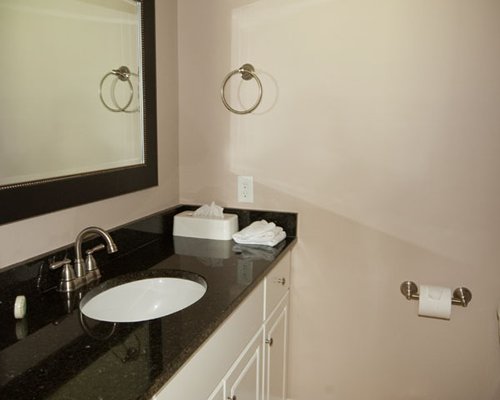 A bathroom with a counter top wash basin and a large mirror.