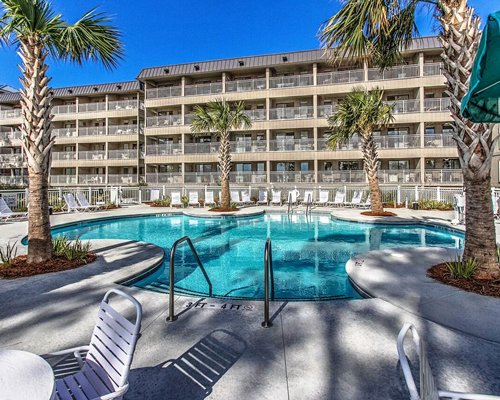 View of balconies swimming pool with palm trees.