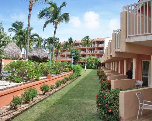 Aruba Beach Club ground floor view of balconies surrounded by lawn and trees.