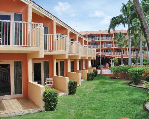 Aruba Beach Club ground floor view of balconies surrounded by lawn and trees.