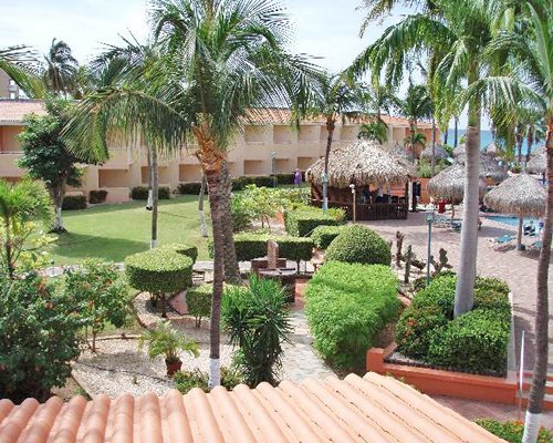 View of balconies and ocean alongside swimming pool, thatched sunshades and lawn.