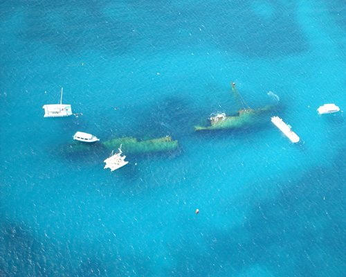 An aerial view of clear ocean waters with boats and yachts.