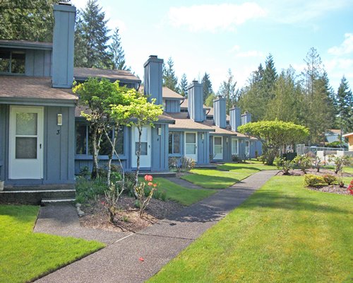 Multiple units of Blue Heron Resort alongside lawn near wooded area.