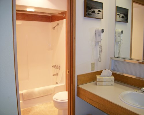 A bathroom with open vanity and enclosed toilet and bathing area.