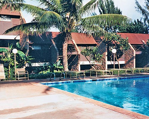 An outdoor swimming pool with palm trees and nearby resort units.