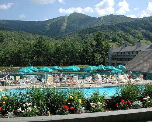 Outdoor swimming pool with chaise lounge chairs surrounded by mountains.