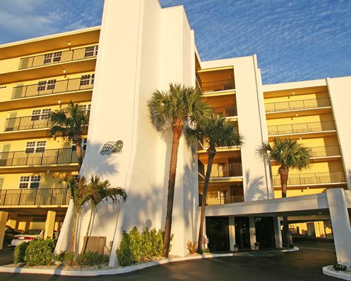 A street view of a multi-story resort unit alongside palm trees.