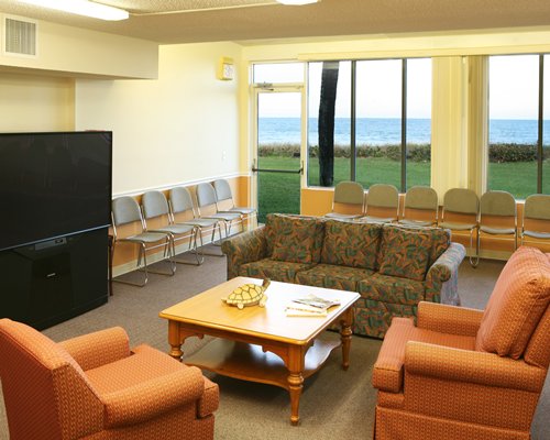 A well furnished common room with sofa, television, and patio chairs.