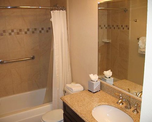 A bathroom with open vanity, toilet, and bathing area.