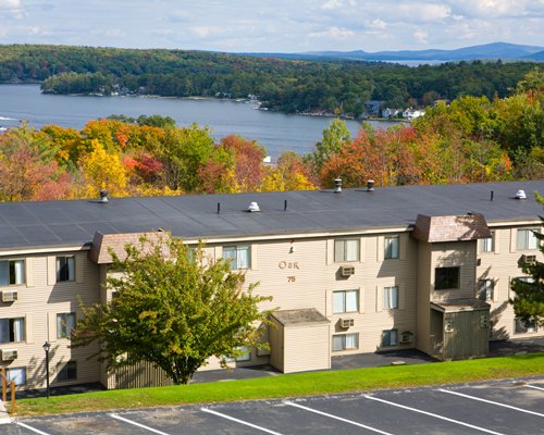 Multi-story units with parking, surrounded by wooded area near lake.
