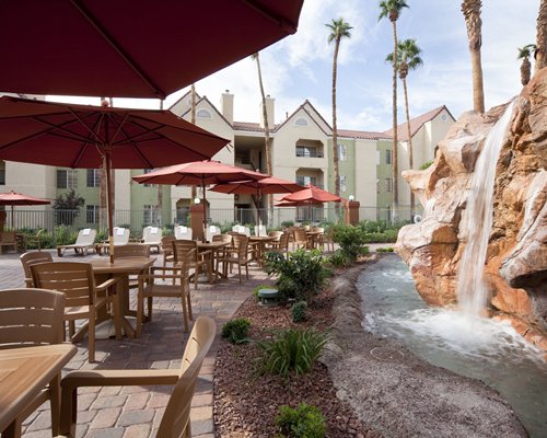 An outdoor swimming pool with palm trees and nearby resort units.