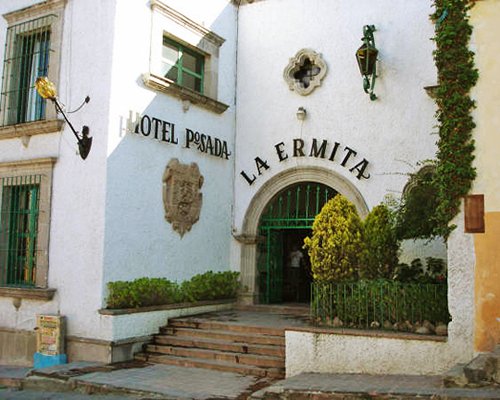 Exterior view of Condo Hotel Posada La Ermita resort with shrubs.