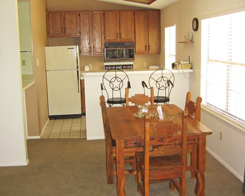 A well furnished dining room alongside a kitchen with a breakfast bar.