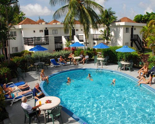 An outdoor swimming pool surrounded by lounge and palm trees alongside resort.