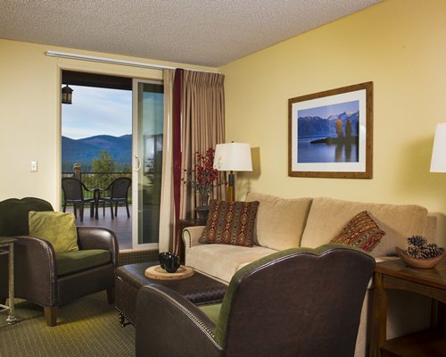 A well furnished living room with a balcony and mountain view.