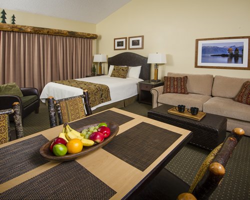 An open plan unit with a queen bed couch and a dining area.