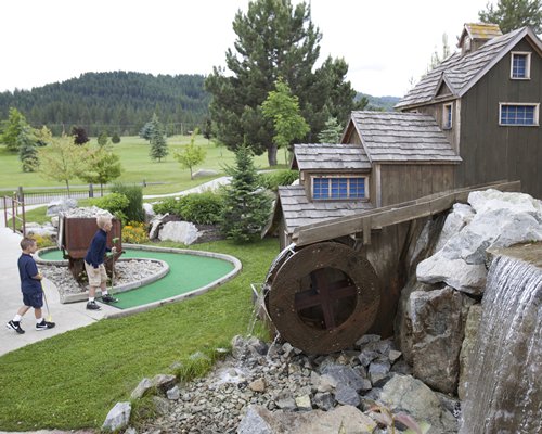 Miniature golf course with fountain and forest view.