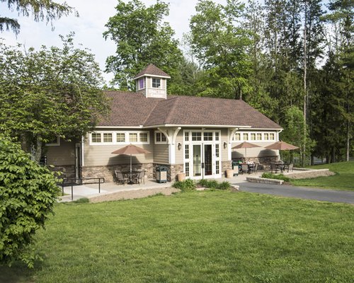 Restaurant with outdoor dining surrounded by lawn and woods.