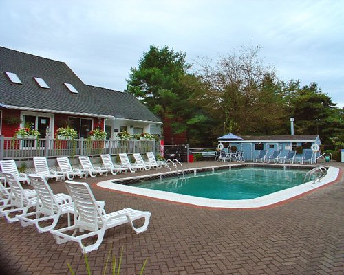 Outdoor swimming pool with chaise lounge chairs and patio table.