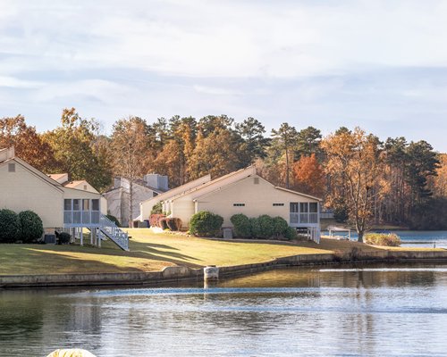 A lake view of multiple units surrounded by lawns and trees.