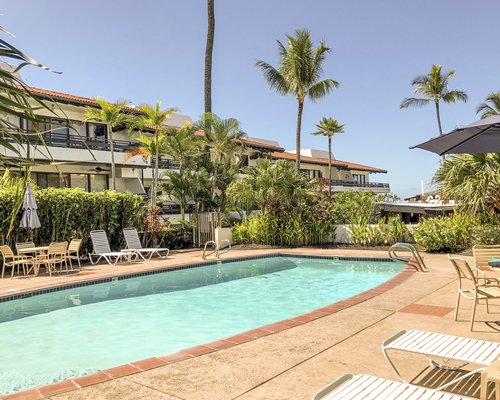 An outdoor swimming pool with lounges alongside multi story balconies.