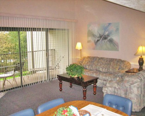 Living room with open plan dining area and balcony with landscaped outdoor view.