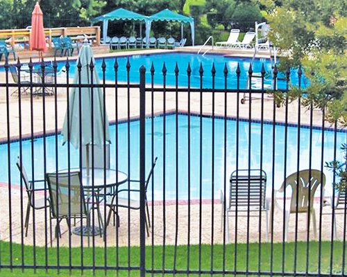 Outdoor swimming pool for adults and kids with chaise lounge chairs and patio tables.