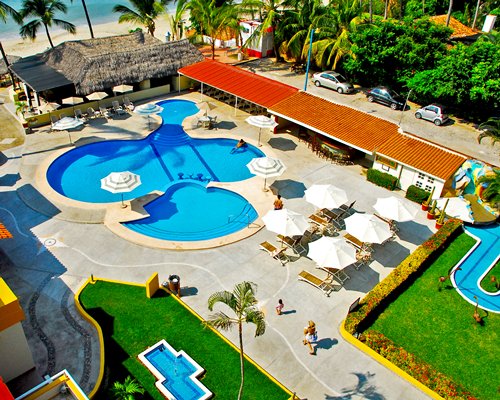 An aerial view of outdoor swimming pool with sunshade lounge near the ocean.