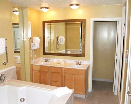 A bathroom with a bathtub and double sink vanity.
