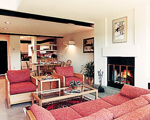 A well furnished living room with dining area and fire in the fireplace.