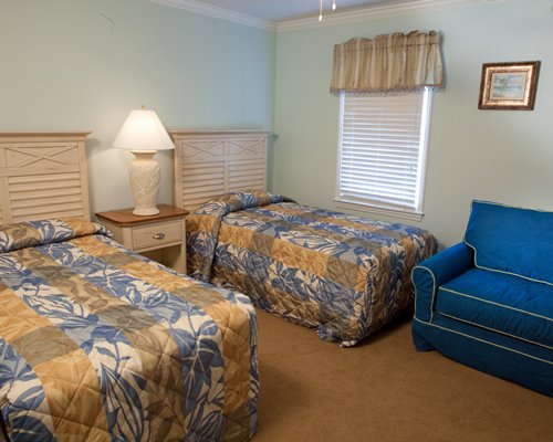 Furnished bedroom with two twin beds a chair and outside view.