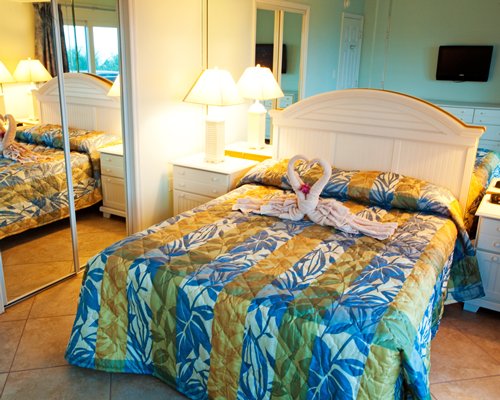 Two towels crafted as a heart placed on a queen bed.
