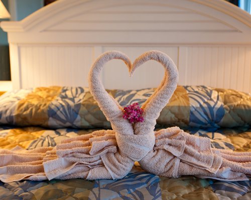 Two towels crafted as a heart placed on a queen size bed.