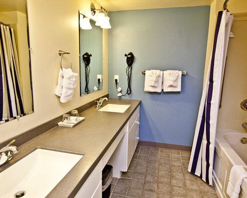 A bathroom with double sink vanity with a bathtub.