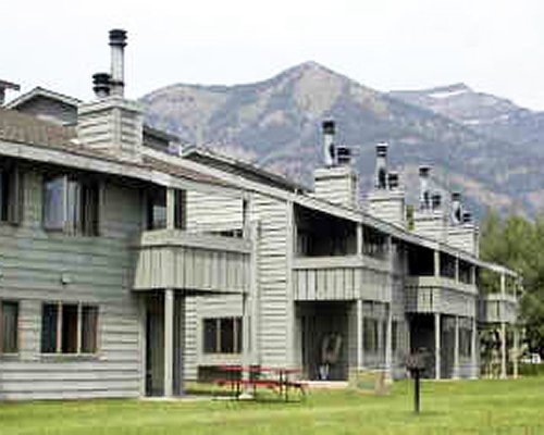 Exterior view of multi story condos alongside mountain.