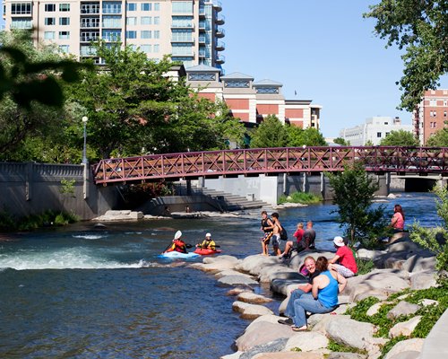 People kayaking in a stream flowing under the bridge.