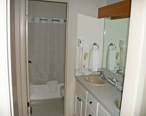 A bathroom with shower and bathtub with double sink vanity.