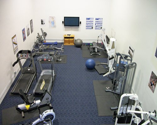 A well equipped indoor fitness center with a television.